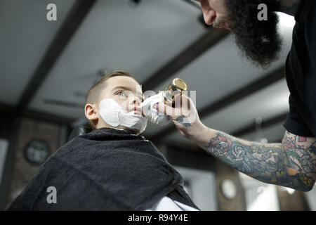 Kinder Friseur Schneiden kleiner Junge vor einem dunklen Hintergrund. Zufriedene cute Vorschüler Boy, die Haare schneiden lassen. Stockfoto