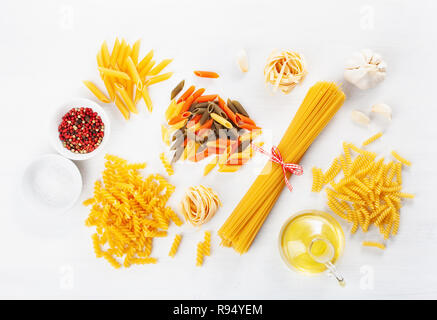 Verschiedene rohe Nudeln flach auf Weiß. Spaghetti fusilli Penne tagliatelle Girandole Stockfoto