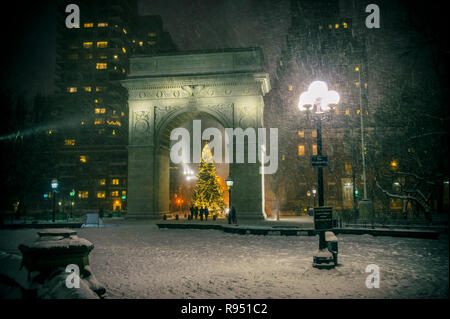 Winterurlaub Nacht Blick auf den Washington Square Park mit einem Weihnachtsbaum unter fallenden Schnee in New York City Stockfoto