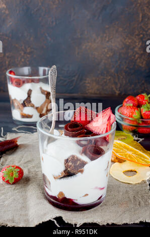 Schokolade Cookies, Sahne und Erdbeeren Nachtisch in einem Glas auf einem darkbackground, leckere Kleinigkeit, Kopie Raum Stockfoto