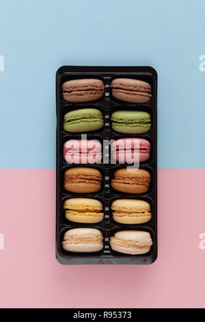 Bunte Französische macarons in Paket auf rosa-blauen Hintergrund-Bild vertikal Stockfoto