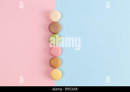 Reihe von bunten Französische macarons auf rosa-blauen Hintergrund mit Kopie Raum Stockfoto