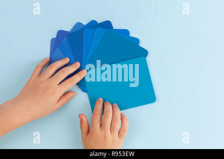 Die Hand des Kindes spielen mit farbmuster Karten - Schattierungen von Blau. Ansicht von oben mit der Kopie Raum Stockfoto