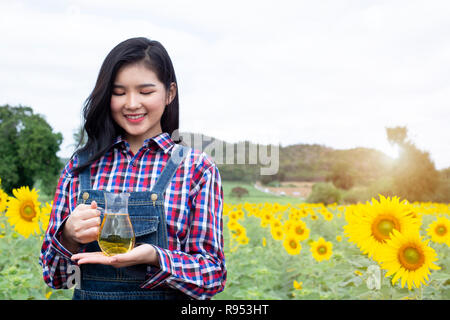 Junge Frauen eine Flasche Öl gegen Sonnenblumen - Bild Stockfoto