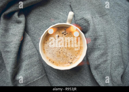 Eine Tasse cooffee auf Textil grauer Hintergrund mit bokeh Wirkung. Kaffee Zeit. Flach Stil. Stockfoto