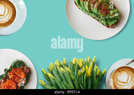 Zwei Tassen Kaffee, Sandwiches und einen Strauß Blumen auf eine helle Fläche. Festliche Konzept. Frühlingsferien. Stockfoto