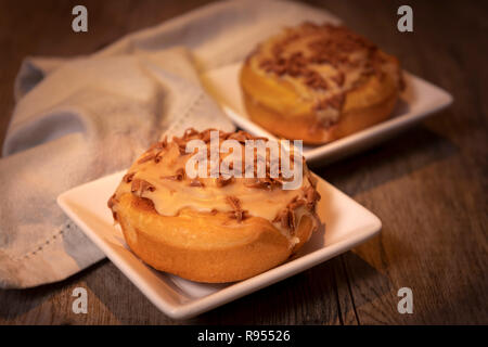 Süße Brötchen mit Zimt und Schokolade Sahnehäubchen auf einem Holztisch Stockfoto