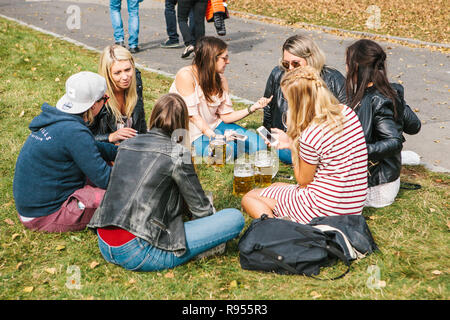 Prag, 23. September 2017: Feier der traditionellen deutschen Bier Festival namens Oktoberfest in der Tschechischen Republik. Junge Mädchen Freunde sitzen auf dem Gras sprechen und trinken frisches Bier Stockfoto