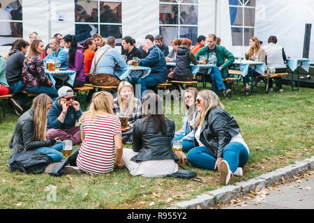 Prag, 23. September 2017: Feier der traditionellen deutschen Bier Festival namens Oktoberfest in der Tschechischen Republik. Junge Mädchen Freunde sitzen auf dem Gras sprechen und trinken frisches Bier Stockfoto