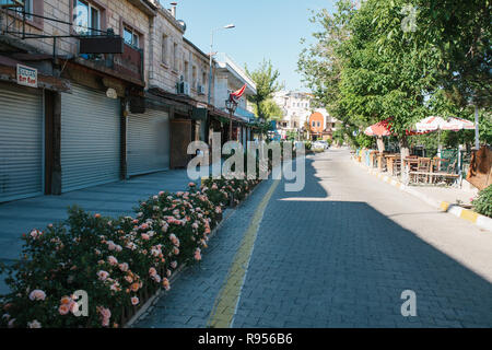 Sonniger Morgen in Göreme - Straße mit Blumen und geschlossene Geschäfte und leere Straße Cafés Stockfoto