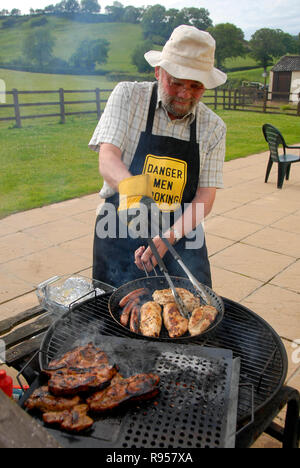 Älterer Mann kochen Fleisch am Grill Stockfoto