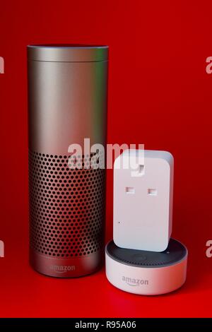 Amazon Echo, Echo Dot und Smart Plug auf rotem Hintergrund Stockfoto