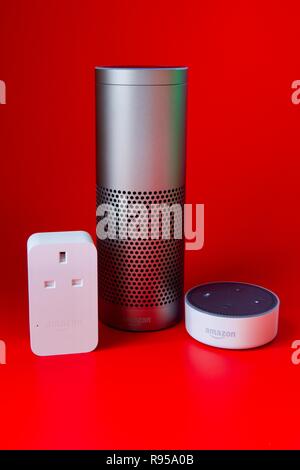Amazon Echo, Echo Dot und Smart Plug auf rotem Hintergrund Stockfoto