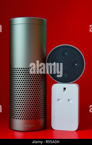 Amazon Echo, Echo Dot und Smart Plug auf rotem Hintergrund Stockfoto