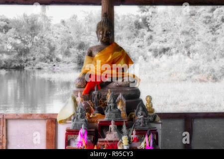 Dieses einzigartige Bild zeigt ein Buddha Statue auf einem See. Die budha hat eine orangefarbene Kap. Stockfoto