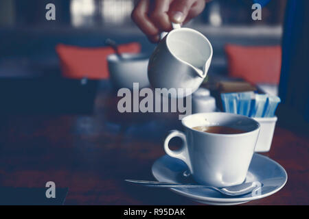Gießen Milch in die Tasse Kaffee Stockfoto
