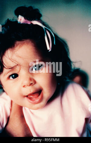 Baby Mädchen Kind sitzt und macht lustige Gesichter Stockfoto