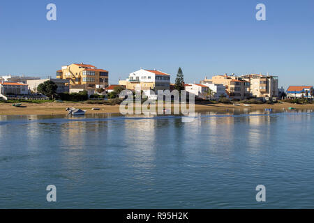 Faro, Portugal.der Strand auf der Ria Formosa Lagunenseite der Insel Faro, Portugal, Boote in der Lagune und Wohngebäude im Hintergrund Stockfoto