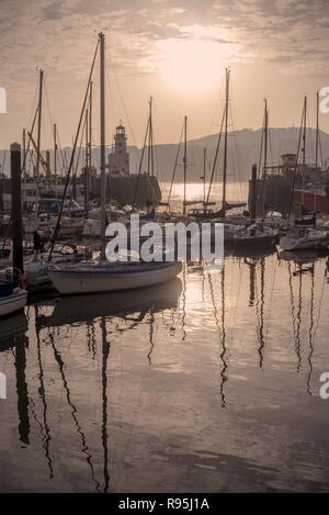 Den Hafen und Jachthafen in Scarborough. Die Boote sind in der Silhouette und die Masten und am Morgen die Sonne im Wasser spiegelt. Stockfoto
