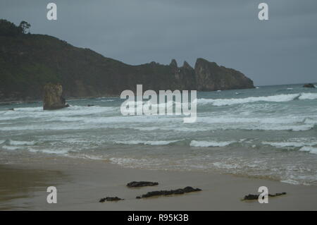 Schuss der Wellen an den Strand und einem schönen Felsen am Strand von El Aguilar an einem regnerischen Tag. Juli 29, 2015. Landschaften, Natur, Reisen. Stockfoto