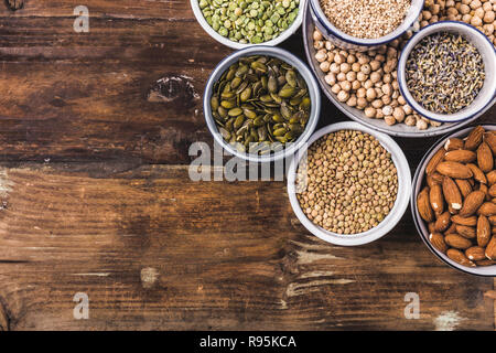 Zusammensetzung der verschiedenen Arten von Hülsenfrüchten in Schalen auf Holz- Hintergrund Stockfoto