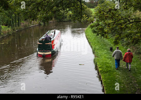 Um GROSSBRITANNIEN - Zwei Wanderer mit ihrem Hund durch einen Kanal Lastkahn auf dem Lancaster Canal weitergeleitet werden Stockfoto