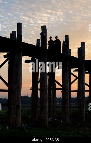 Buddhistische Mönche gehen Sie auf die U-Bein Brücke bei Sonnenaufgang, Amarapura, Mandalay, Myanmar, Myanmar Stockfoto
