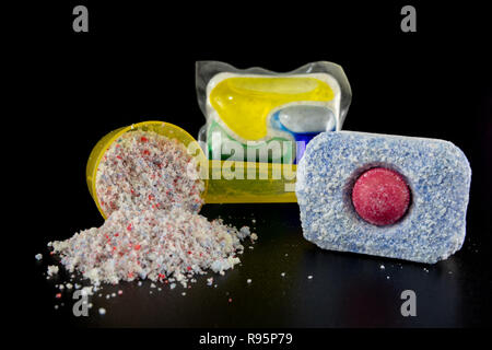 Pulver und Tabletten für die Spülmaschine auf dem Küchentisch. Reinigungsmittel für Haushaltsgeschirrspüler. Der dunkle Hintergrund. Stockfoto