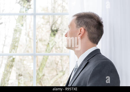 Closeup Profil, Seite von jungen Menschen, männlich Geschäftsmann in Grau, grauer Anzug, Krawatte, Bräutigam, in Heim, Haus, Wohnung, weiß Curt Stockfoto