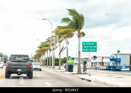 Key West, USA - Mai 1, 2018: Overseas Highway Road, US1, Autos Verkehrszeichen für Palm Avenue, erste Straße, nächste Signal, Menschen Wandern, Radfahren auf dem Fahrrad Stockfoto