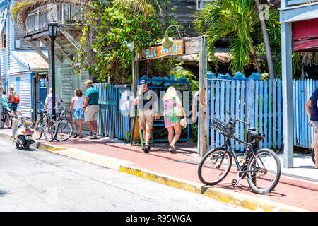 Key West, USA - Mai 1, 2018: die Menschen zu Fuß durch den blauen Himmel, Restaurant, Cafe, Veranstaltungsort serviert karibische Küche, Palmen, Bürgersteig in Florida keys Dow Stockfoto
