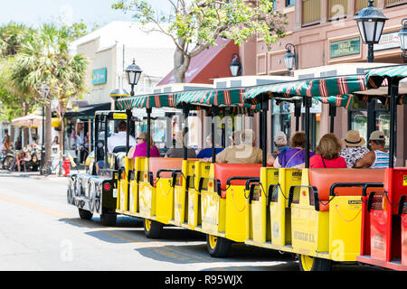 Key West, USA - Mai 1, 2018: Zurück von Menschen, Touristen, gelb schwarz Conch train geführte Tour Bus, Trolleybus mit Guide Treiber in Florida keys Stadt Stockfoto