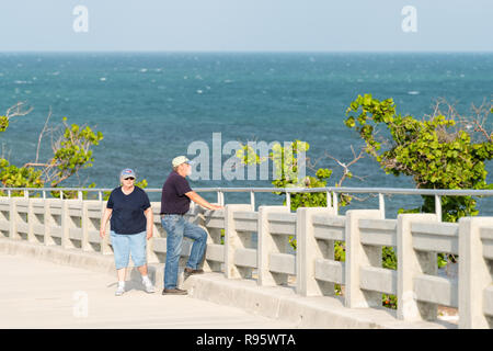 Bahia Honda Key, USA - Mai 1, 2018: Ältere, Alte, ältere Paare gehen, stehen auf heruntergekommenen verlassenen Brücke mit Ozean, Meer Wasser Wellen in Sta anzeigen Stockfoto