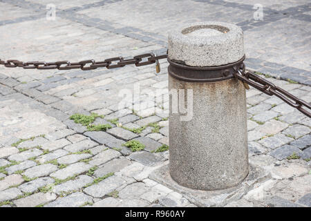 Eine runde Beton Säule ist auf dieser Nahaufnahme gesehen. Eine Kette zu sehen ist die Säule an der Seite der steinboden gebunden. Auf dem Hintergrund, die Strasse ist s Stockfoto