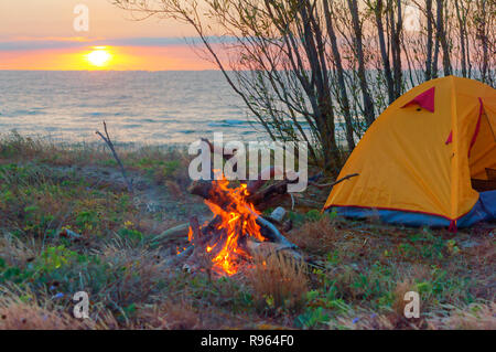 Zelt und Feuer am Strand, gelbe Zelt und Feuer Stockfoto