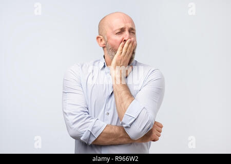 Sleepy reifer Mann Gähnen nach einem harten Arbeitstag, sein Mund schließen mit Hand Stockfoto