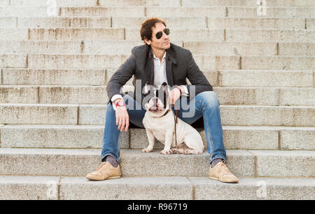 Städtische Szene. Mann verkleidet in Freizeitkleidung auf einige Treppen neben seinem Hund posing Stockfoto