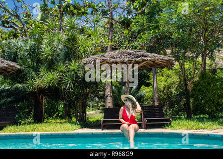 Dame in Rot durch den Pool Stockfoto