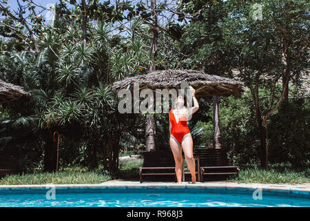 Dame in Rot durch den Pool Stockfoto