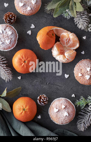 Ansicht von oben in der Tabelle mit satsumas, mit Zucker bestreut Muffins und Christmas Star Cookies auf dunkel strukturierten Hintergrund Stockfoto