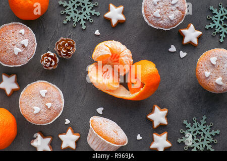 Ansicht von oben in der Tabelle mit satsumas, mit Zucker bestreut Muffins und Christmas Star Cookies auf dunkel strukturierten Hintergrund Stockfoto