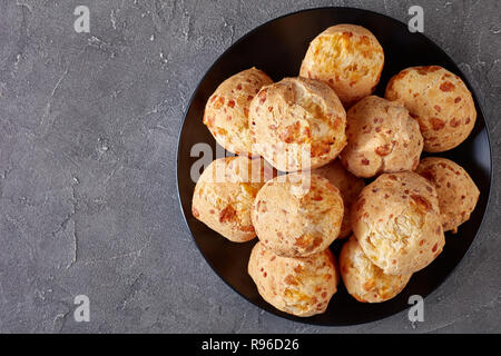 Ansicht von oben von Gougeres, Käse Puffs Kugeln auf schwarzem Teller. Traditionelle französische Käse choux Brötchen auf einer konkreten Tabelle, Ansicht von oben, flatlay, Cl Stockfoto