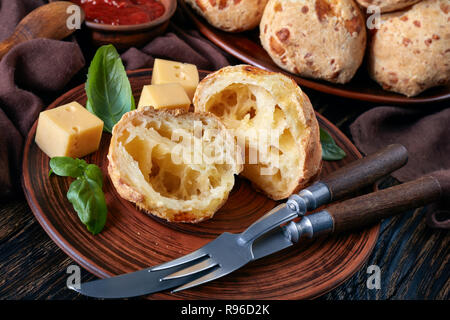 In der Nähe von Gougeres, Käse Puffs Kugeln in Hälften auf einem Steingut Teller geschnitten. Klassische französische Käse choux Brötchen. braun Tuch, Käse und Tomaten Sauce Stockfoto