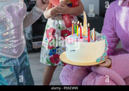 Kinder Parteiunterhalter gibt Lecker helle Kuchen in Form von Fantasy unicorn für Kid feiert Geburtstag mit Freunden eingerichtet. Kinder geburtstag p Stockfoto