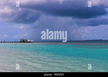 Diese einzigartige Natur Foto zeigt, wie auf den Malediven an einem regnerischen Tag eine Wolke Regen direkt vor der Insel auf das Meer. Stockfoto