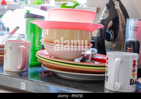 Platten, Teller und Tassen stapelten sich auf einer Küchenarbeitsplatte bereit, gewaschen zu werden. Stockfoto