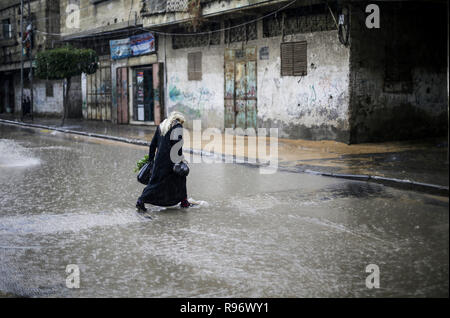 Dezember 20, 2018 - Gaza, Gaza, Palästina - eine Frau gesehen zu Fuß auf eine überschwemmte Straße bei einem schweren Niederschlag in Gaza Stadt. (Bild: © Mahmoud Issa/SOPA Bilder über ZUMA Draht) Stockfoto