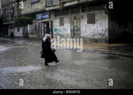 Dezember 20, 2018 - Gaza, Gaza, Palästina - eine Frau gesehen zu Fuß auf eine überschwemmte Straße bei einem schweren Niederschlag in Gaza Stadt. (Bild: © Mahmoud Issa/SOPA Bilder über ZUMA Draht) Stockfoto