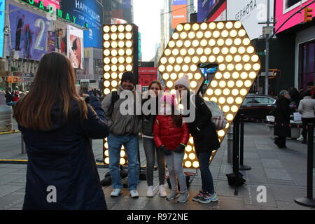 New York, USA. 19 Dez, 2018. Besucher in Times Square vor der beleuchteten 19 für ein Foto. In den kommenden Tagen werden die Zahlen auf einem Hochhaus, um das neue Jahr 2019 gemeinsam mit den bestehenden '2' und '0' gehisst werden. (Dpa''19': Times Square bereitet sich für Silvesterspektakel" vom 20.12.2018) Credit: Christina Horsten/dpa/Alamy leben Nachrichten Stockfoto