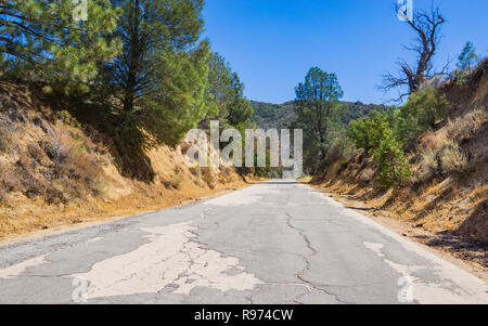 Risse und robuste Straße führt durch bewaldete Hügel im südlichen Kalifornien. Stockfoto